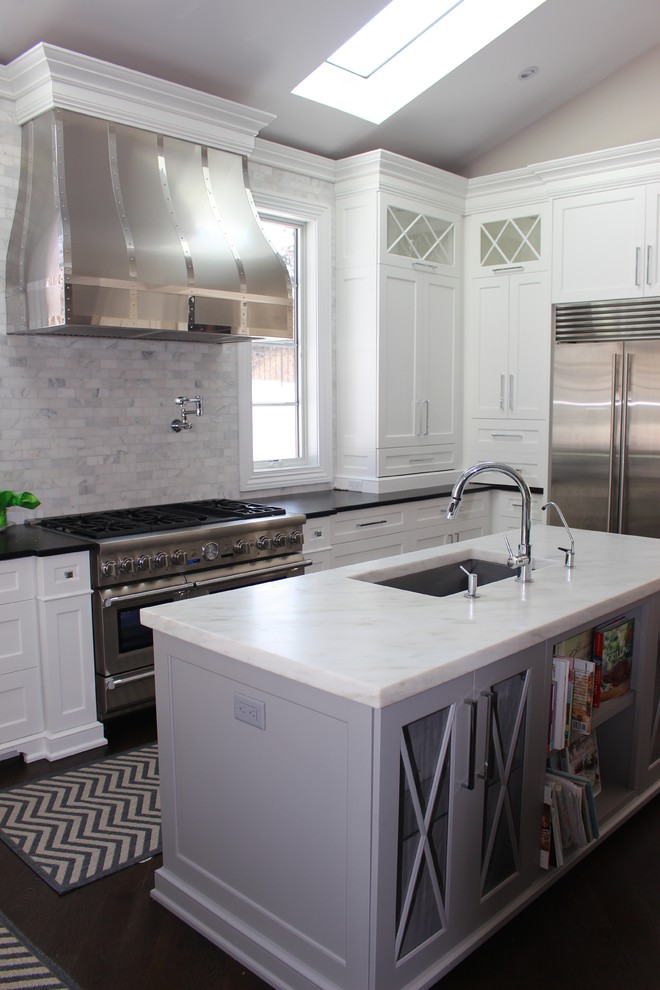 Moderne Küche mit Landhausspüle, Schrankfronten mit vertiefter Füllung, weißen Schränken, Marmor-Arbeitsplatte, Küchenrückwand in Grau, Küchengeräten aus Edelstahl, dunklem Holzboden und zwei Kücheninseln in New York