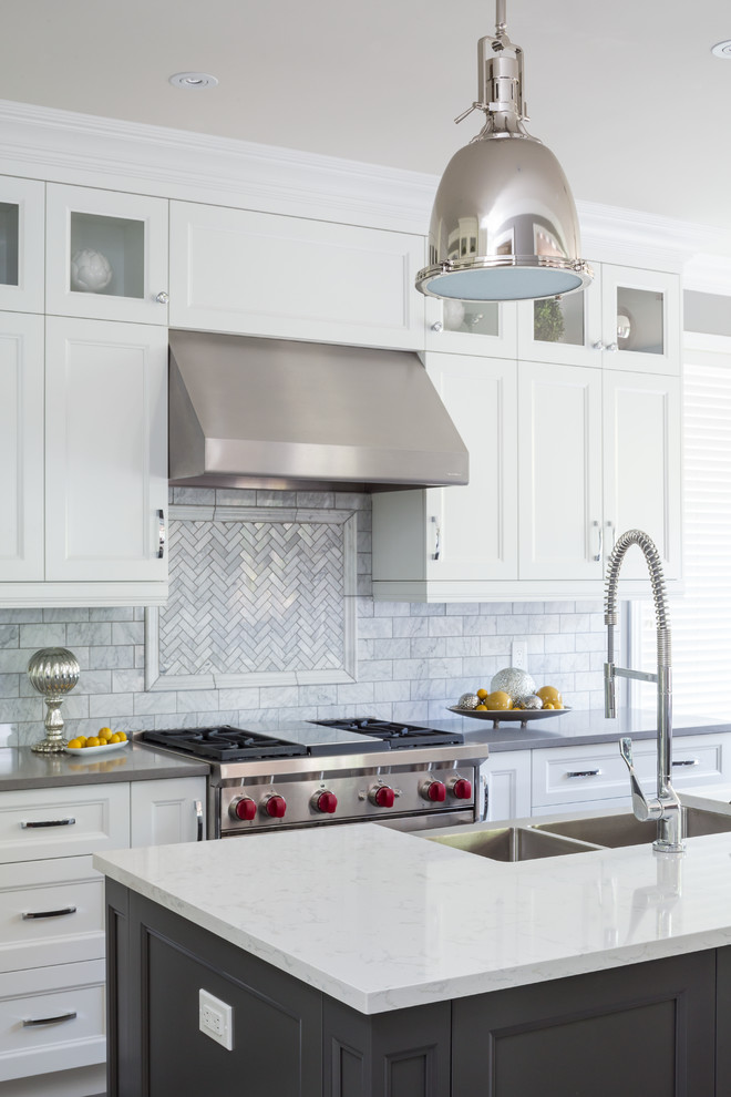 Large transitional galley kitchen photo in Toronto with a farmhouse sink, recessed-panel cabinets, white cabinets, quartz countertops, gray backsplash, stainless steel appliances, an island and marble backsplash