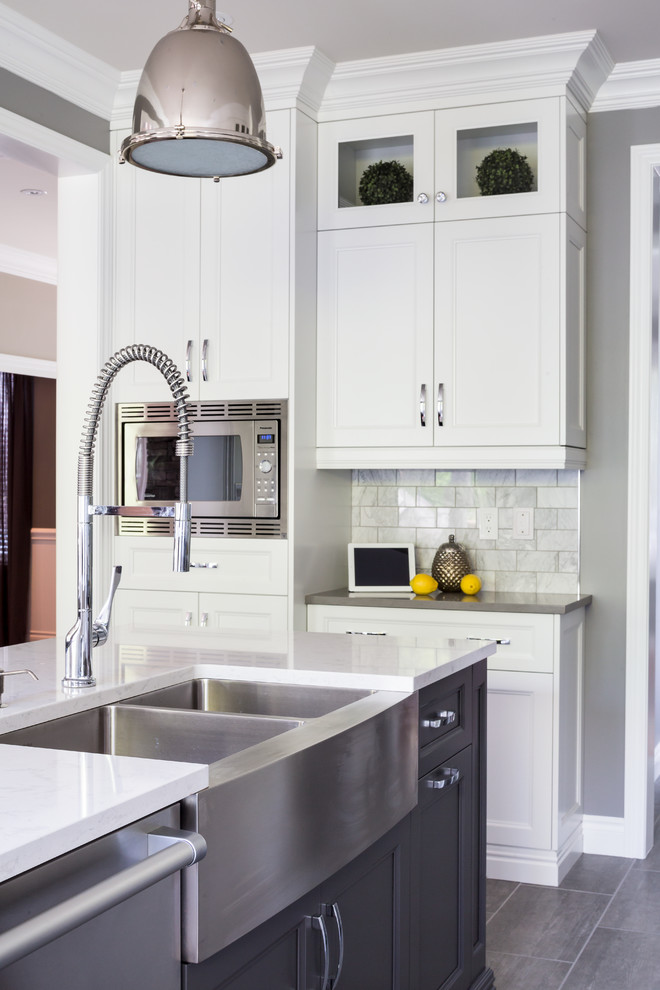 Eat-in kitchen - large transitional l-shaped ceramic tile eat-in kitchen idea in Toronto with a farmhouse sink, recessed-panel cabinets, gray cabinets, quartz countertops, gray backsplash, stone tile backsplash, stainless steel appliances and an island