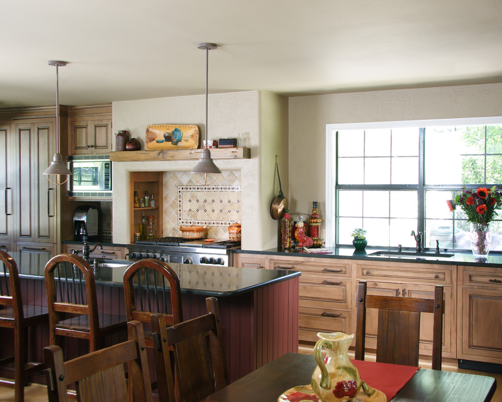 На фото: кухня в классическом стиле с обеденным столом, врезной мойкой, фасадами с выступающей филенкой, фасадами цвета дерева среднего тона, разноцветным фартуком и окном с