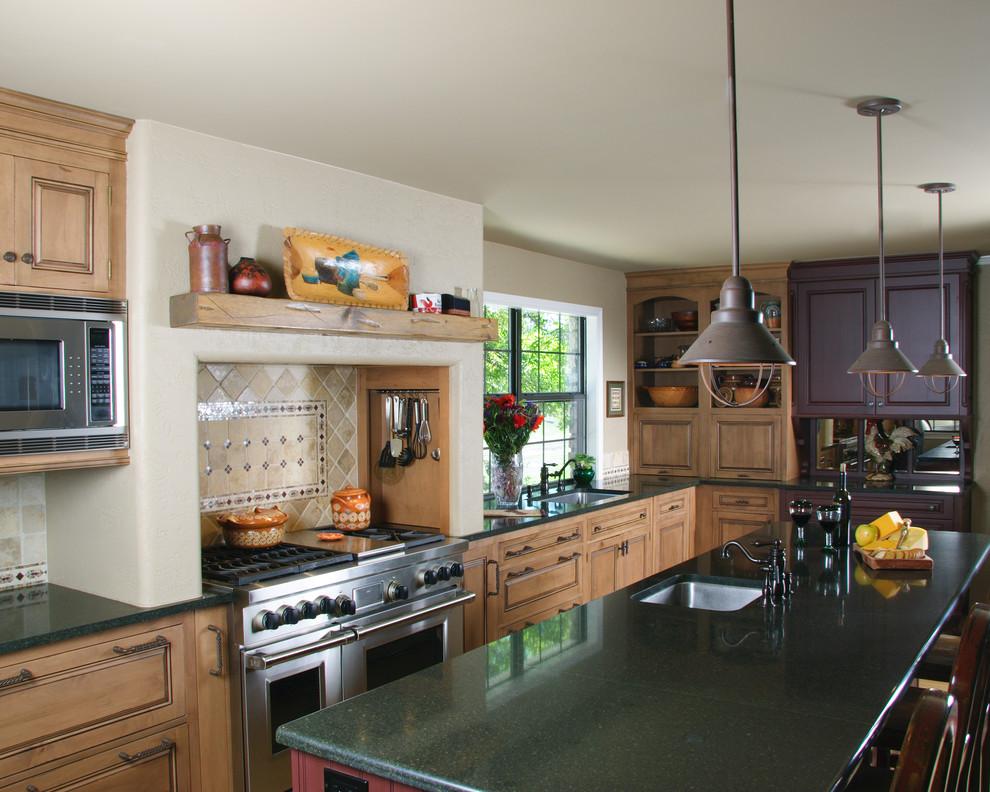 Cette image montre une cuisine chalet en bois clair avec un plan de travail en quartz modifié, un placard avec porte à panneau surélevé et un électroménager en acier inoxydable.
