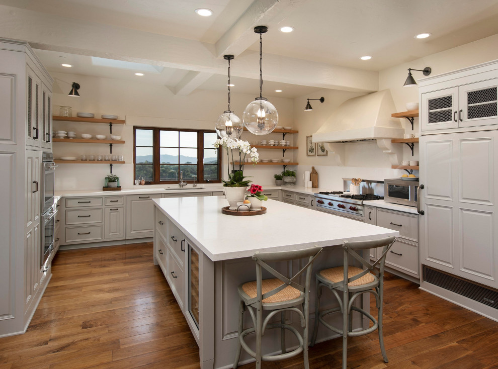 Inspiration for a traditional u-shaped enclosed kitchen in Santa Barbara with a submerged sink, raised-panel cabinets, grey cabinets, white splashback, integrated appliances, medium hardwood flooring, an island, brown floors, white worktops and a coffered ceiling.