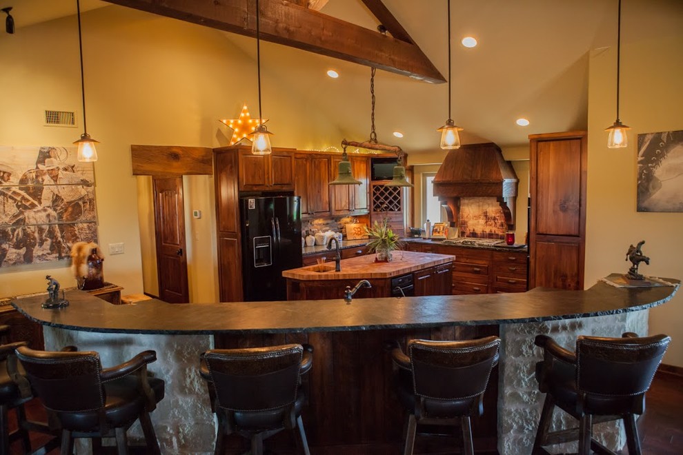 Inredning av ett amerikanskt stort kök, med mörkt trägolv, brunt golv, en undermonterad diskho, luckor med upphöjd panel, skåp i mellenmörkt trä, stänkskydd i stenkakel, svarta vitvaror och flera köksöar