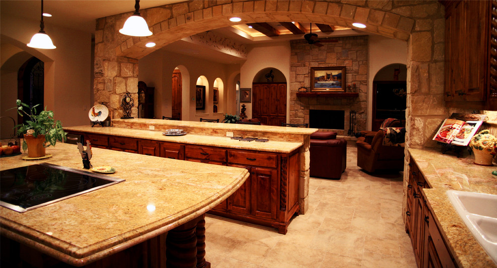 Inspiration for a large mediterranean l-shaped concrete floor open concept kitchen remodel in Austin with a drop-in sink, raised-panel cabinets, dark wood cabinets, granite countertops, beige backsplash, ceramic backsplash and an island