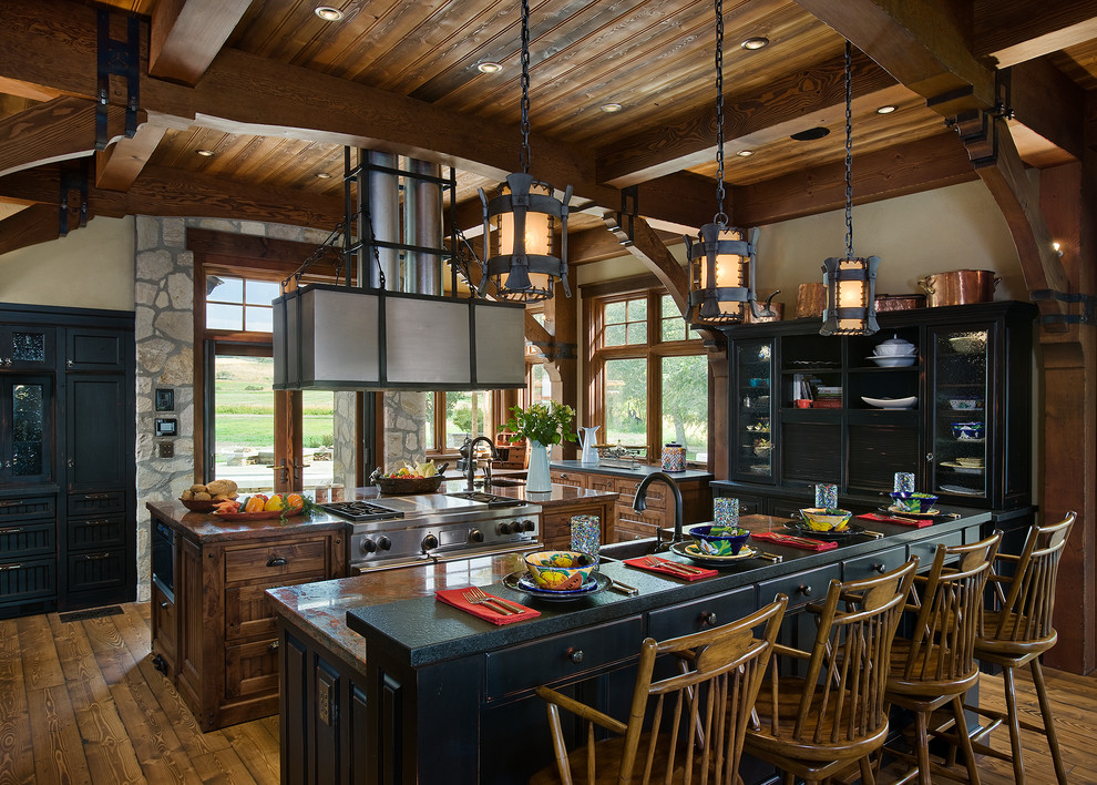 Große Rustikale Küche mit Landhausspüle, Granit-Arbeitsplatte, Küchengeräten aus Edelstahl, braunem Holzboden, zwei Kücheninseln und schwarzen Schränken in Calgary