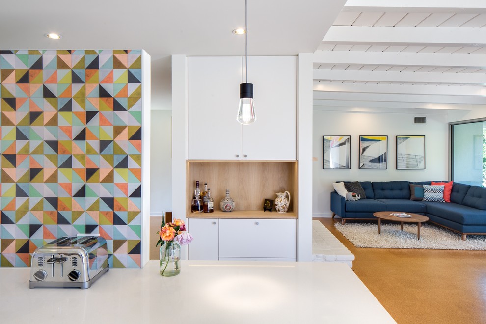 Medium sized retro kitchen in Los Angeles with flat-panel cabinets, white cabinets, engineered stone countertops, multi-coloured splashback, cement tile splashback, an island and brown floors.