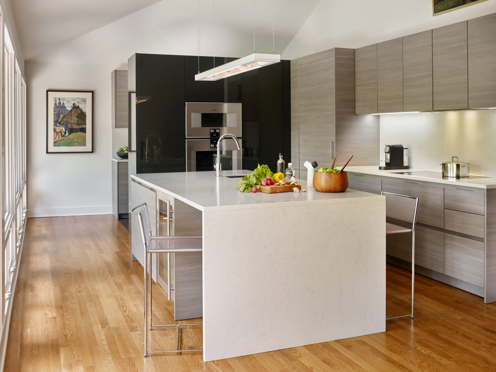 Foto på ett litet funkis vit kök, med en undermonterad diskho, släta luckor, bänkskiva i kvarts, vitt stänkskydd, rostfria vitvaror, en köksö, brunt golv, grå skåp och mellanmörkt trägolv