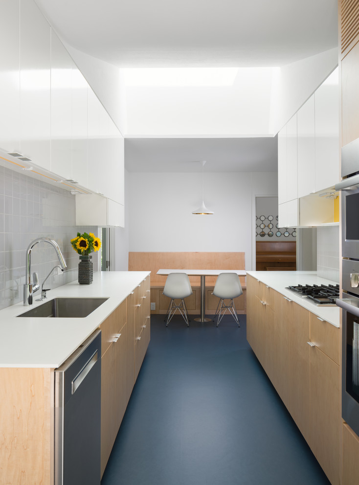 Immagine di una cucina parallela contemporanea con lavello sottopiano, ante lisce, ante in legno chiaro, paraspruzzi grigio e elettrodomestici in acciaio inossidabile
