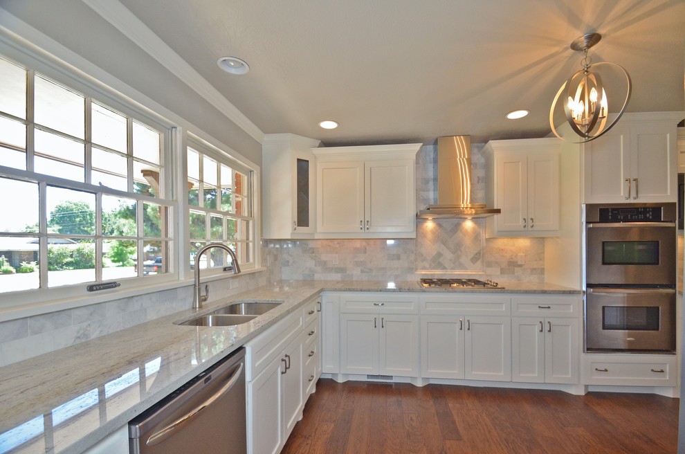 Klassisk inredning av ett mellanstort kök, med en dubbel diskho, skåp i shakerstil, vita skåp, marmorbänkskiva, vitt stänkskydd, rostfria vitvaror, mellanmörkt trägolv och stänkskydd i stenkakel