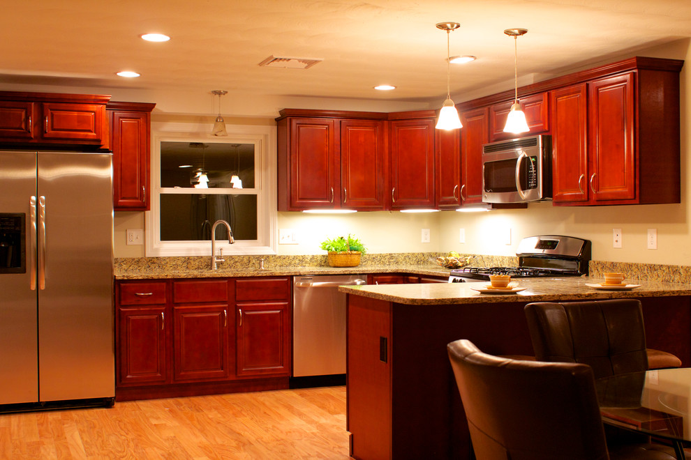 Example of a mid-sized classic u-shaped light wood floor eat-in kitchen design in Boston with raised-panel cabinets, medium tone wood cabinets, granite countertops, stainless steel appliances and a peninsula