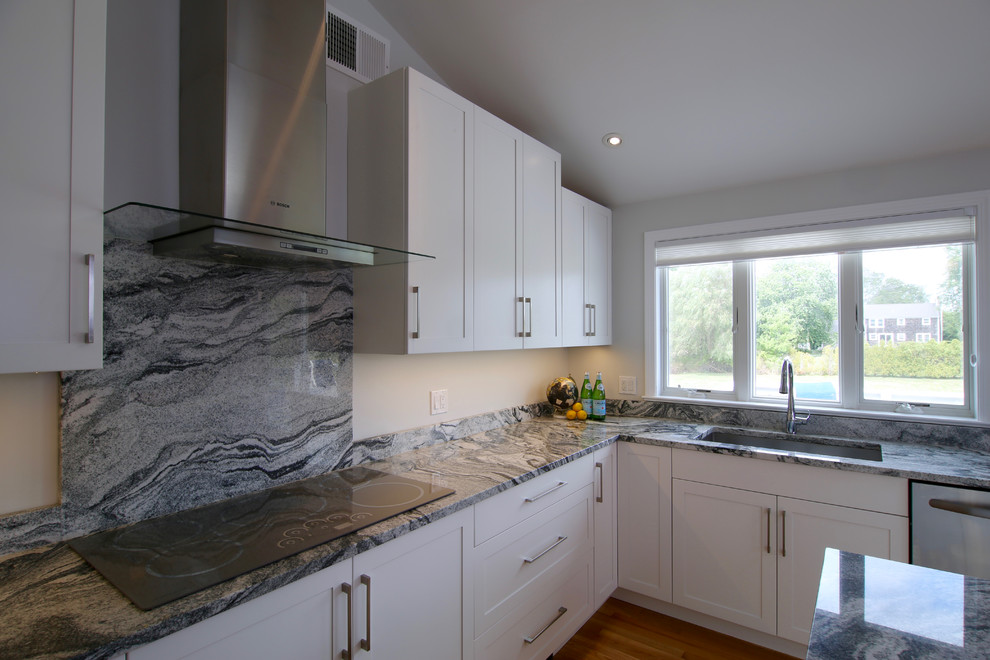 Inredning av ett klassiskt mellanstort kök, med en undermonterad diskho, skåp i shakerstil, vita skåp, granitbänkskiva, vitt stänkskydd, stänkskydd i sten, rostfria vitvaror, mellanmörkt trägolv och en köksö