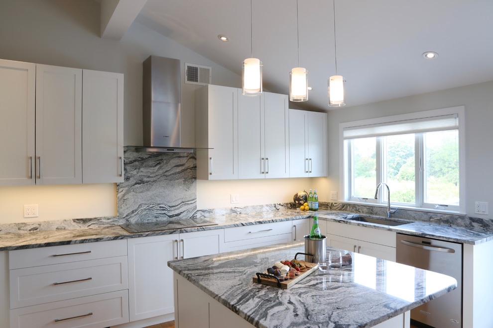 Inspiration for a mid-sized transitional u-shaped medium tone wood floor eat-in kitchen remodel in Providence with an undermount sink, shaker cabinets, white cabinets, granite countertops, white backsplash, stone slab backsplash, stainless steel appliances and an island