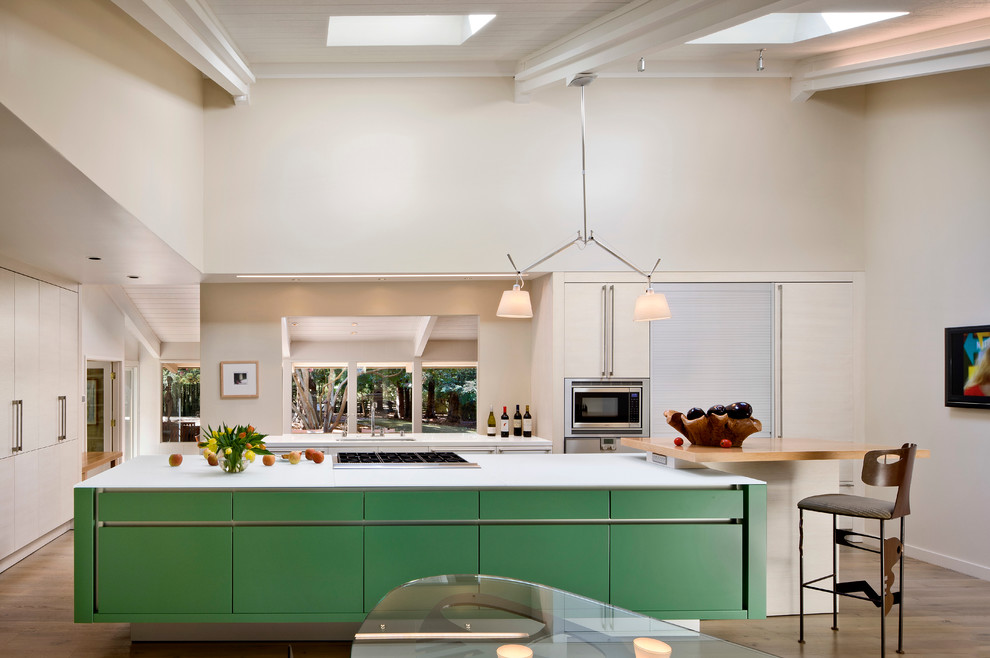 Bild på ett retro kök, med en undermonterad diskho, gröna skåp, rostfria vitvaror, släta luckor och träbänkskiva