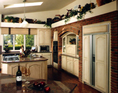 Geschlossene, Mittelgroße Klassische Küche mit profilierten Schrankfronten, beigen Schränken, Granit-Arbeitsplatte, schwarzen Elektrogeräten, dunklem Holzboden und Kücheninsel in San Diego