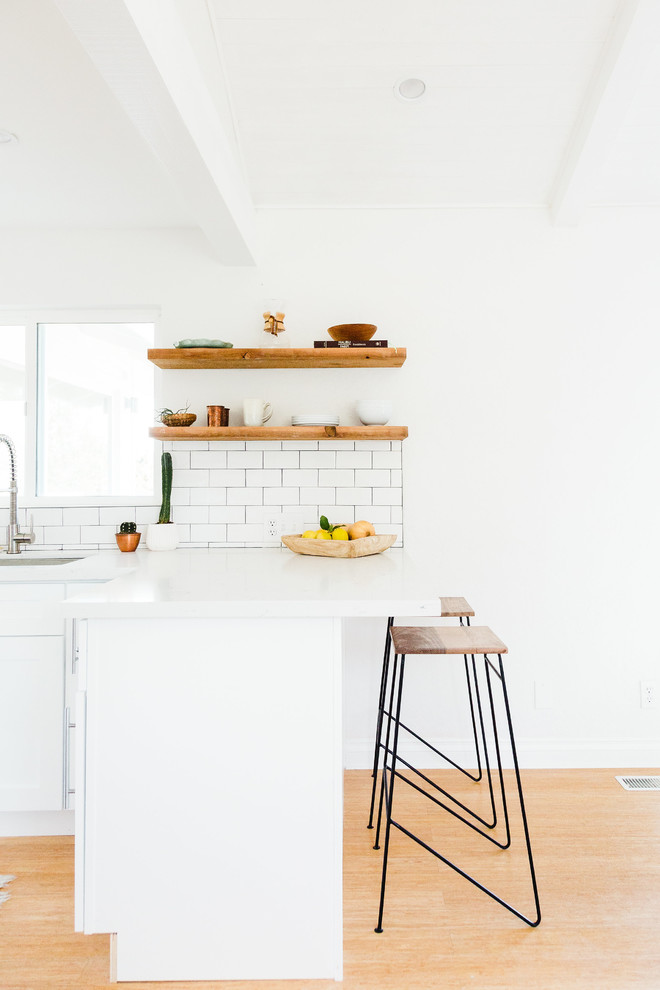Inspiration for a scandinavian bamboo floor kitchen remodel in San Diego with a single-bowl sink, shaker cabinets, white cabinets, quartzite countertops, subway tile backsplash and stainless steel appliances