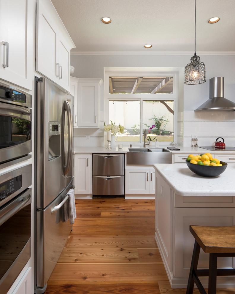 Eat-in kitchen - mid-sized modern l-shaped light wood floor eat-in kitchen idea in San Diego with a farmhouse sink, shaker cabinets, yellow cabinets, granite countertops, white backsplash, ceramic backsplash, stainless steel appliances and an island