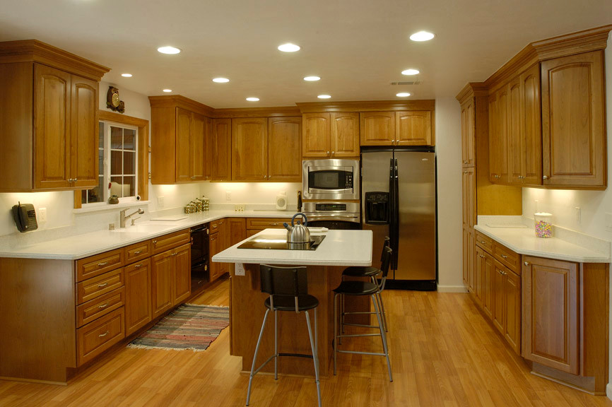 Eat-in kitchen - large traditional u-shaped eat-in kitchen idea in Sacramento with an integrated sink, raised-panel cabinets, medium tone wood cabinets, solid surface countertops, white backsplash, stainless steel appliances and an island