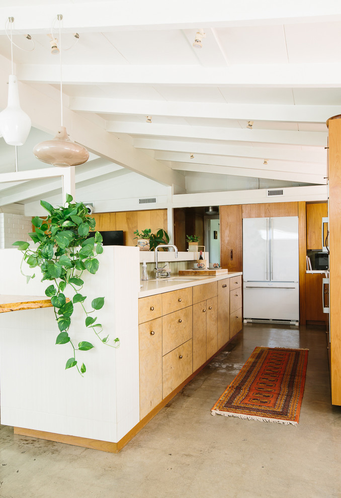 Bild på ett mellanstort 60 tals kök, med en undermonterad diskho, släta luckor, skåp i mellenmörkt trä, bänkskiva i kvarts, grönt stänkskydd, stänkskydd i keramik, vita vitvaror, betonggolv, en köksö och grått golv