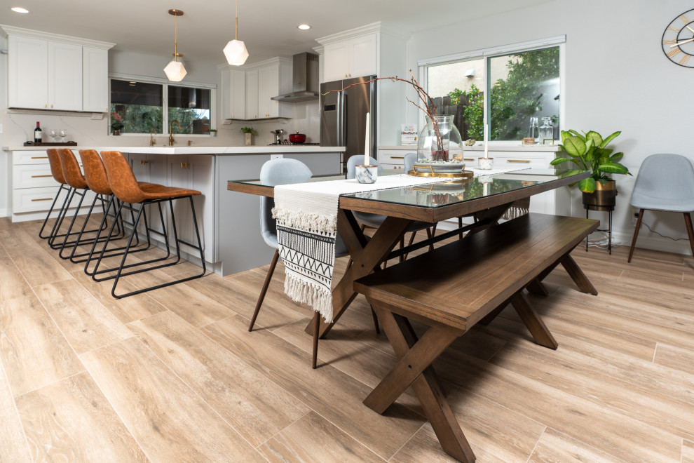 Example of a large transitional l-shaped porcelain tile and brown floor eat-in kitchen design in San Diego with an undermount sink, shaker cabinets, white cabinets, quartz countertops, white backsplash, stainless steel appliances, an island and white countertops