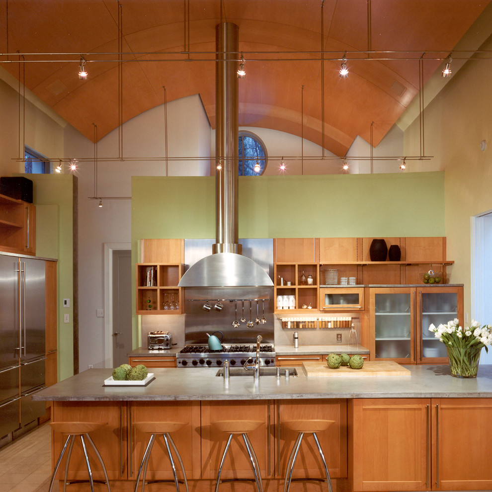 На фото: большая параллельная кухня-гостиная в стиле модернизм с врезной мойкой, плоскими фасадами, светлыми деревянными фасадами, столешницей из бетона, техникой из нержавеющей стали и островом