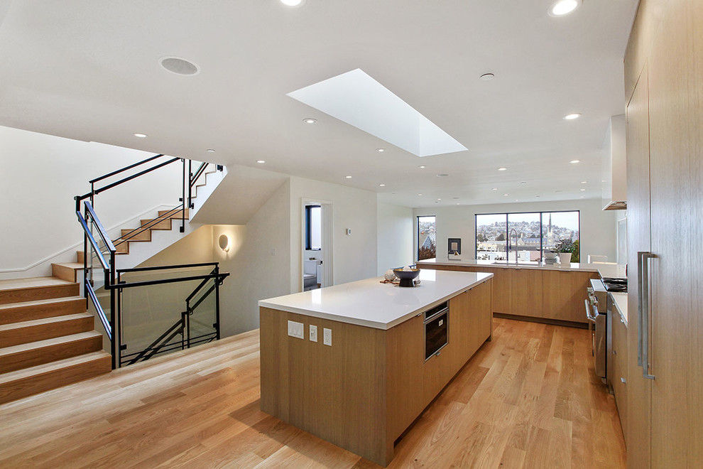 Example of a large minimalist l-shaped light wood floor and brown floor open concept kitchen design in San Francisco with an undermount sink, flat-panel cabinets, medium tone wood cabinets, quartz countertops, paneled appliances and an island