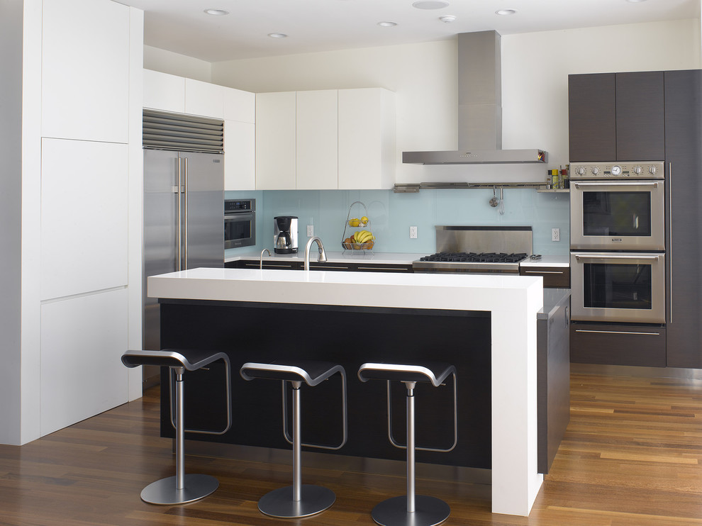 Eat-in kitchen - mid-sized modern l-shaped dark wood floor and brown floor eat-in kitchen idea in San Francisco with glass sheet backsplash, stainless steel appliances, flat-panel cabinets, white cabinets, blue backsplash, quartzite countertops and an island