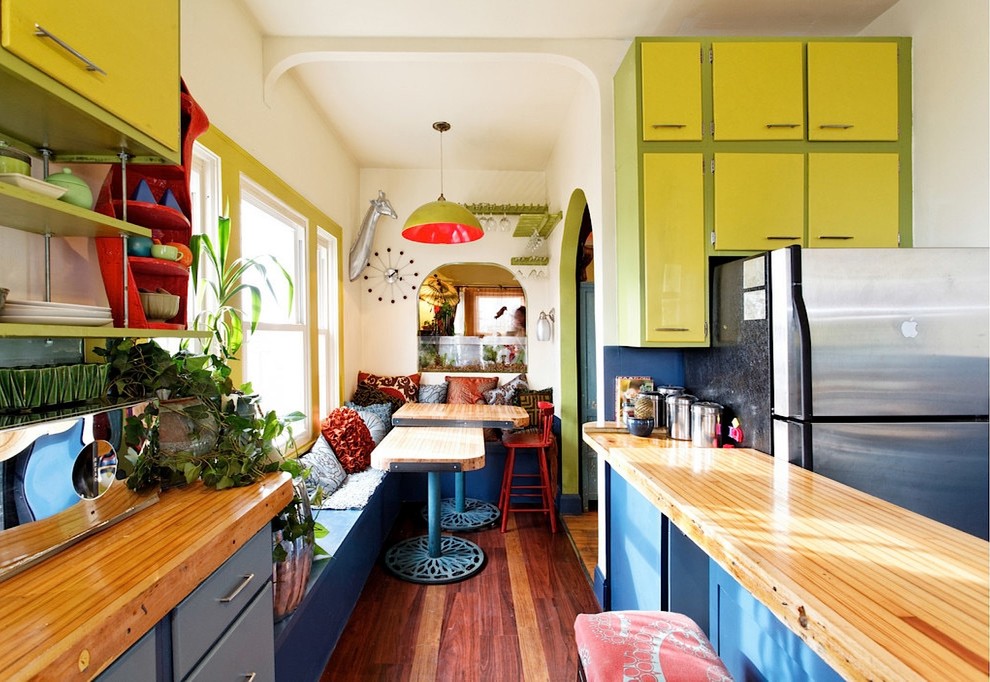 Стильный дизайн: параллельная кухня среднего размера в стиле фьюжн с обеденным столом, плоскими фасадами, зелеными фасадами, деревянной столешницей, техникой из нержавеющей стали, темным паркетным полом, полуостровом и коричневым полом - последний тренд