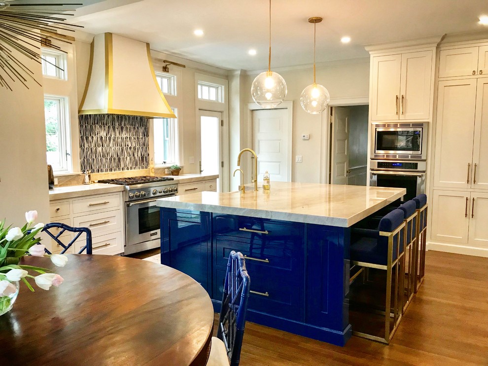 Bild på ett stort funkis kök, med släta luckor, vita skåp, bänkskiva i kvartsit, blått stänkskydd, stänkskydd i glaskakel, rostfria vitvaror och en köksö