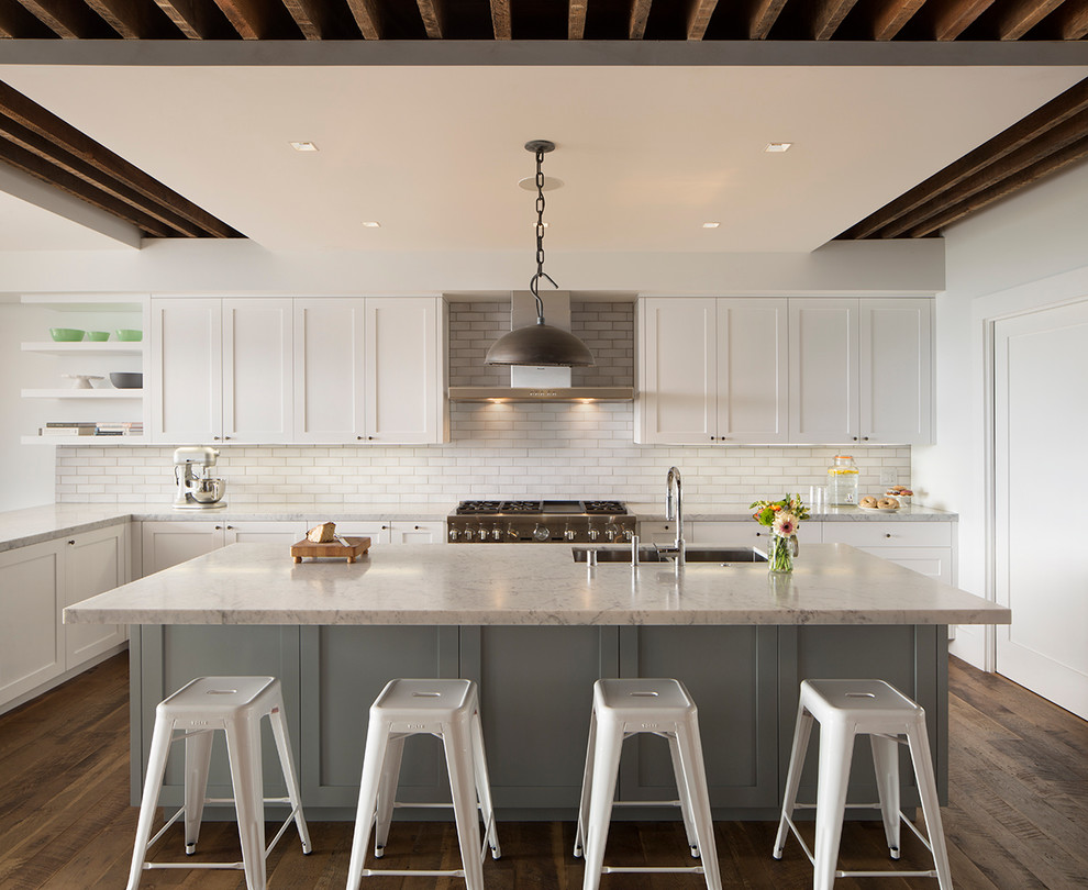 Transitional l-shaped medium tone wood floor kitchen photo in San Francisco with an undermount sink, shaker cabinets, white cabinets, white backsplash, subway tile backsplash, stainless steel appliances and an island
