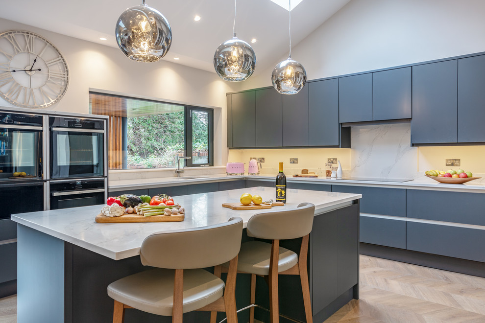 Immagine di una cucina minimal con lavello sottopiano, ante lisce, ante blu, paraspruzzi bianco, elettrodomestici neri, parquet chiaro, pavimento beige e top bianco