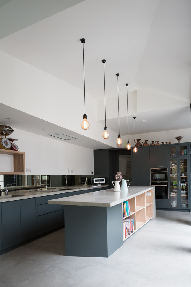 Mittelgroße Moderne Küche mit Betonarbeitsplatte, Rückwand aus Spiegelfliesen, schwarzen Elektrogeräten, Kücheninsel, grauer Arbeitsplatte, Betonboden und grauem Boden in Dublin