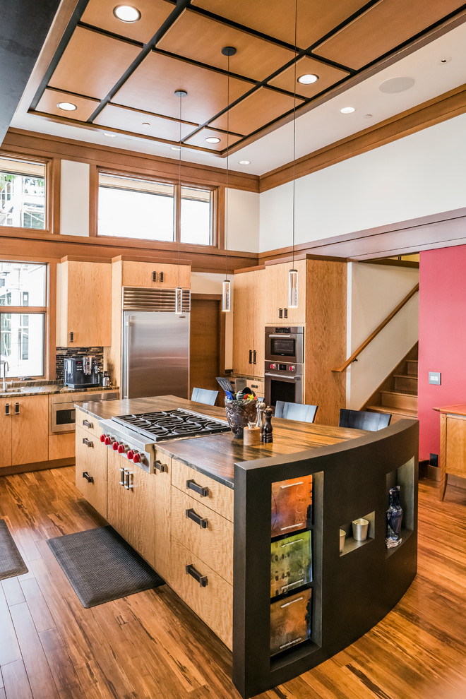 Mittelgroße Retro Küche mit flächenbündigen Schrankfronten, hellbraunen Holzschränken, Küchengeräten aus Edelstahl, braunem Holzboden und Kücheninsel in Seattle