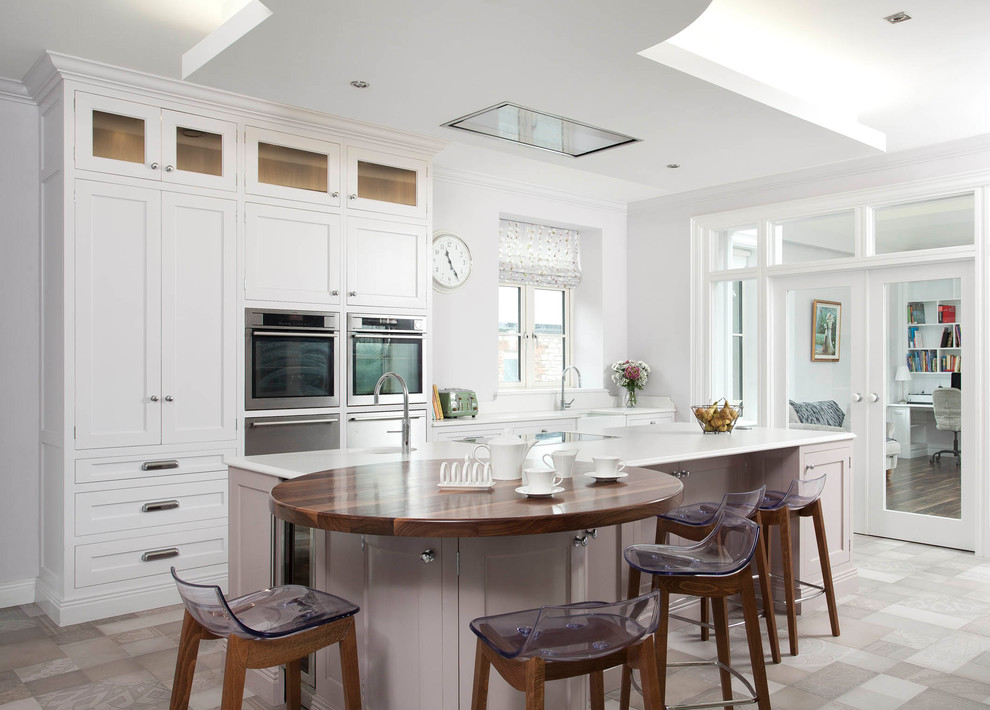 Medium sized traditional l-shaped open plan kitchen in Dublin with a belfast sink, shaker cabinets, yellow cabinets, quartz worktops, stainless steel appliances, an island and white worktops.