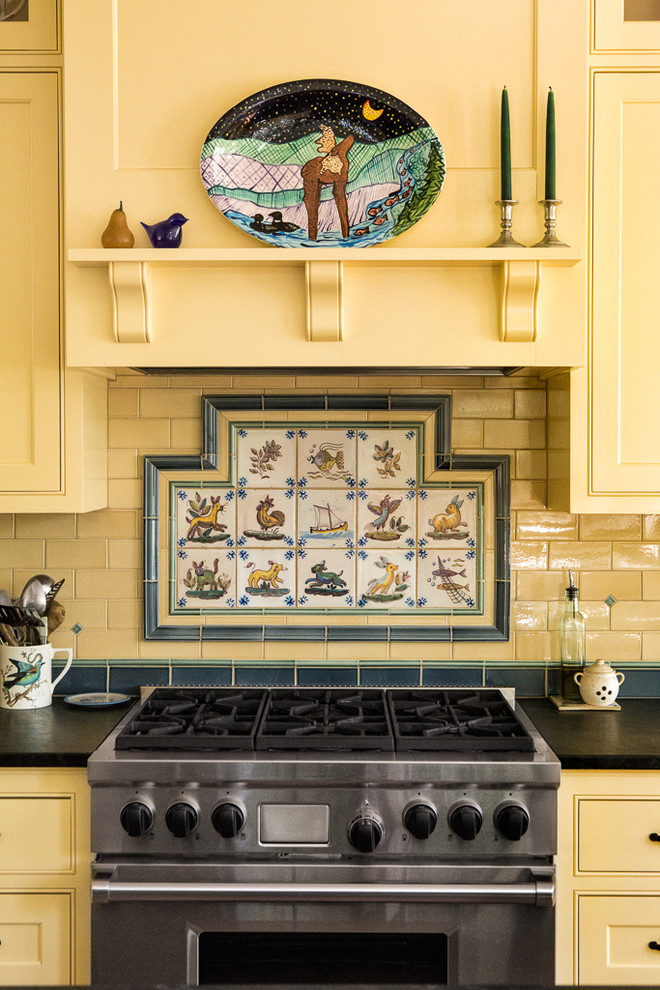 Cette image montre une cuisine traditionnelle avec un placard à porte affleurante, des portes de placard jaunes, une crédence multicolore et un électroménager en acier inoxydable.