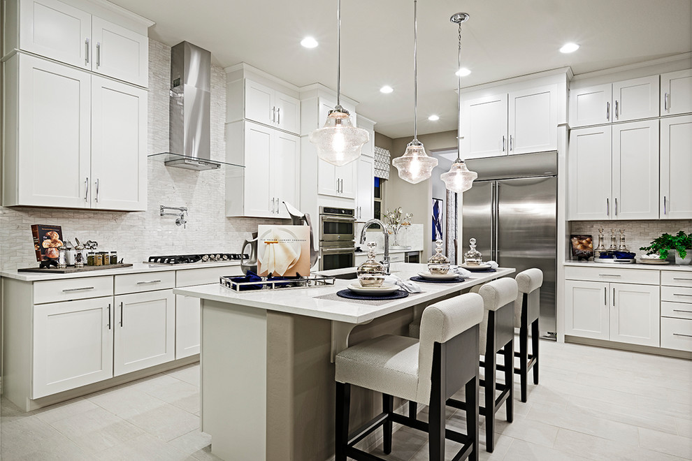 Cette image montre une cuisine design avec des portes de placard blanches, une crédence grise, un électroménager en acier inoxydable, îlot, un sol gris et un plan de travail blanc.