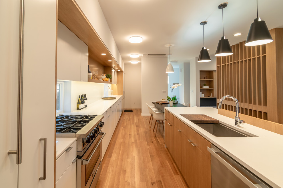 Idéer för att renovera ett mellanstort funkis vit linjärt vitt kök med öppen planlösning, med en undermonterad diskho, släta luckor, vita skåp, bänkskiva i kvarts, vitt stänkskydd, stänkskydd i sten, vita vitvaror, mellanmörkt trägolv, en köksö och vitt golv