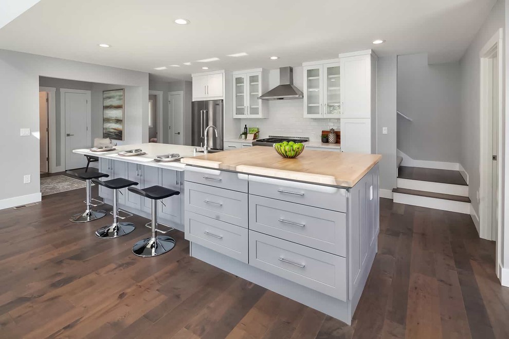 Inspiration for a classic kitchen in Seattle with grey cabinets, white splashback, metro tiled splashback, stainless steel appliances, dark hardwood flooring, an island, brown floors, white worktops and shaker cabinets.