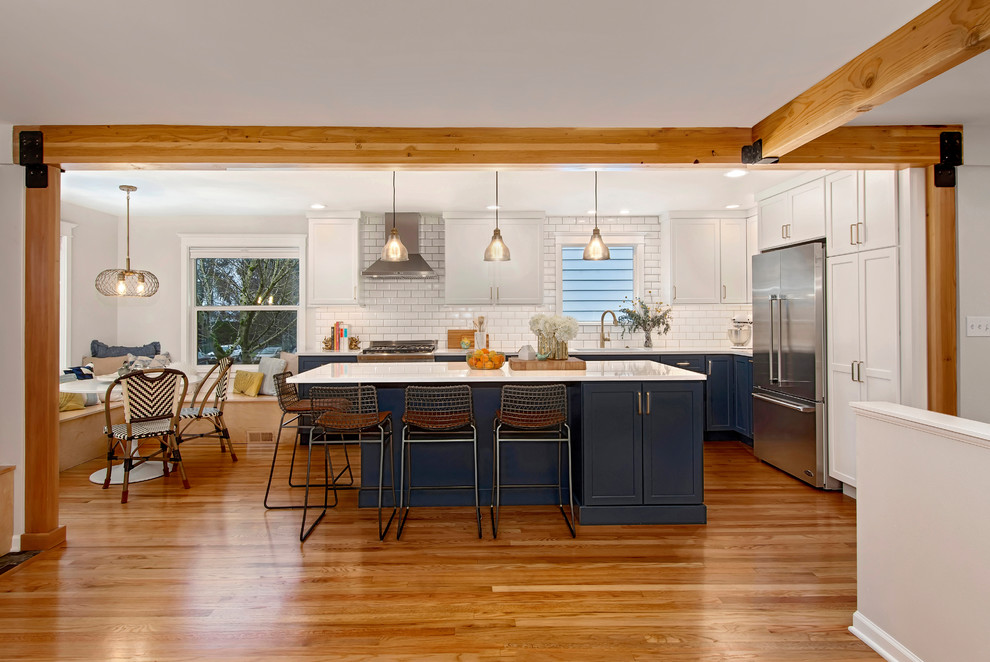 Mid-sized arts and crafts l-shaped medium tone wood floor and brown floor eat-in kitchen photo in Seattle with an undermount sink, flat-panel cabinets, blue cabinets, quartz countertops, white backsplash, ceramic backsplash, stainless steel appliances, an island and white countertops