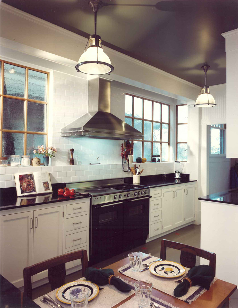 Foto på ett mellanstort amerikanskt kök, med en undermonterad diskho, luckor med infälld panel, vita skåp, marmorbänkskiva, vitt stänkskydd, stänkskydd i tunnelbanekakel, svarta vitvaror och linoleumgolv