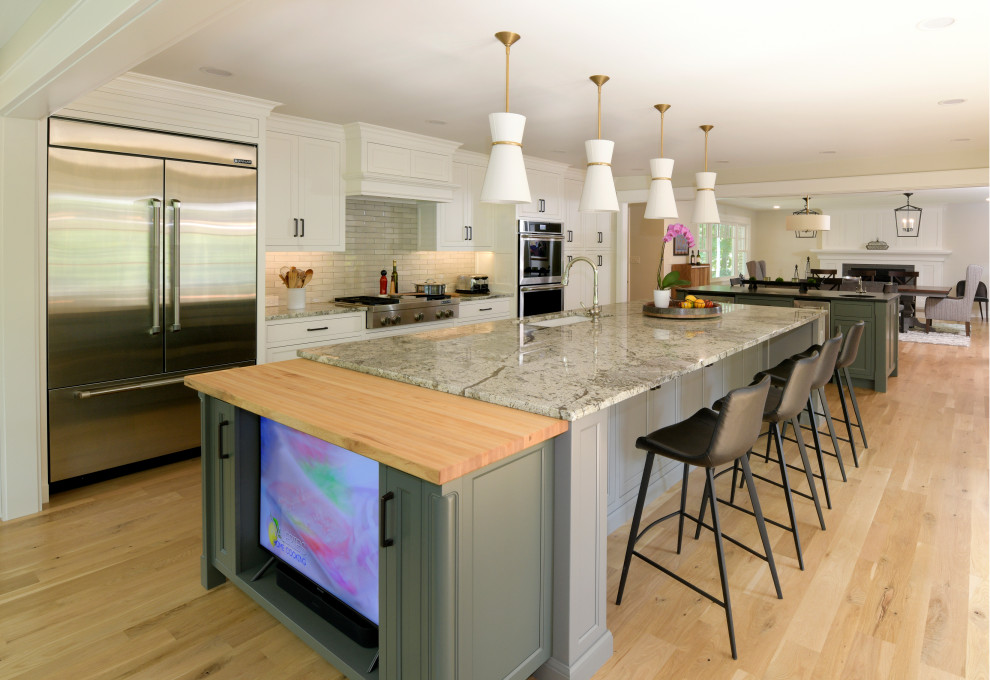 Photo of a medium sized classic single-wall kitchen/diner in Columbus with a submerged sink, beaded cabinets, white cabinets, granite worktops, beige splashback, ceramic splashback, stainless steel appliances, light hardwood flooring, multiple islands, beige floors and beige worktops.
