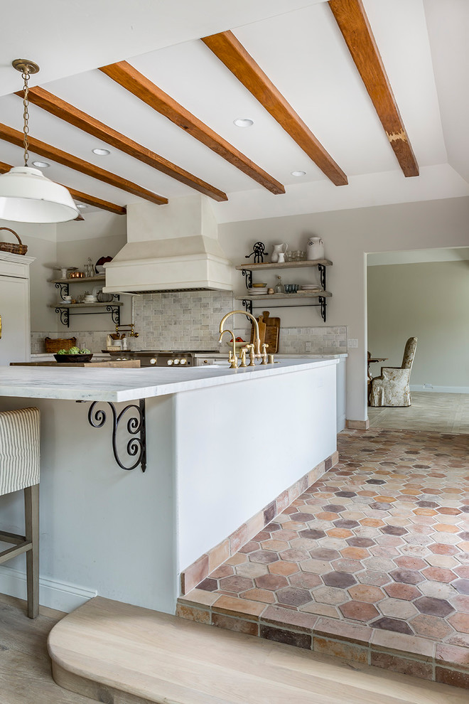 Inspiration for a mid-sized rustic galley cement tile floor and red floor open concept kitchen remodel in San Diego with a single-bowl sink, raised-panel cabinets, white cabinets, marble countertops, gray backsplash, ceramic backsplash, stainless steel appliances and an island
