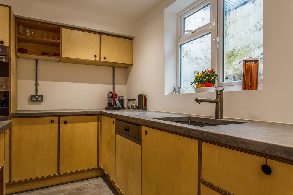 Kleine Stilmix Wohnküche in L-Form mit flächenbündigen Schrankfronten, Betonarbeitsplatte, Küchengeräten aus Edelstahl, Kücheninsel und grauer Arbeitsplatte in Sussex