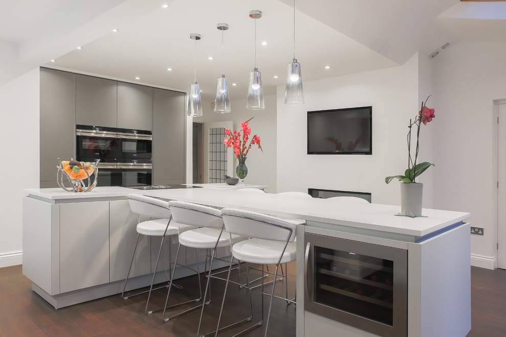 Medium sized contemporary kitchen in Essex with flat-panel cabinets, white cabinets, dark hardwood flooring, an island, brown floors and white worktops.