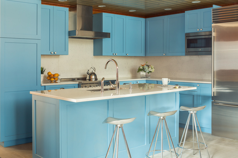 Идея дизайна: кухня в стиле неоклассика (современная классика) с фасадами в стиле шейкер, синими фасадами, столешницей из кварцевого агломерата, белым фартуком, техникой из нержавеющей стали и островом