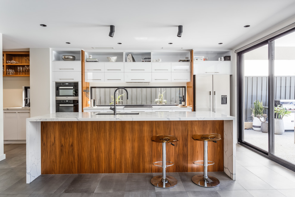 Offene, Zweizeilige Moderne Küche mit flächenbündigen Schrankfronten, weißen Schränken, Marmor-Arbeitsplatte, Rückwand-Fenster, schwarzen Elektrogeräten, Kücheninsel und grauem Boden in Perth