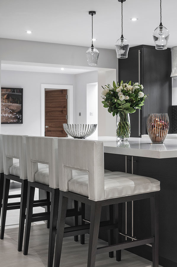 Foto på ett stort funkis kök, med släta luckor, svarta skåp, bänkskiva i kvartsit, grått stänkskydd, stänkskydd i metallkakel, rostfria vitvaror, klinkergolv i keramik, en köksö och beiget golv