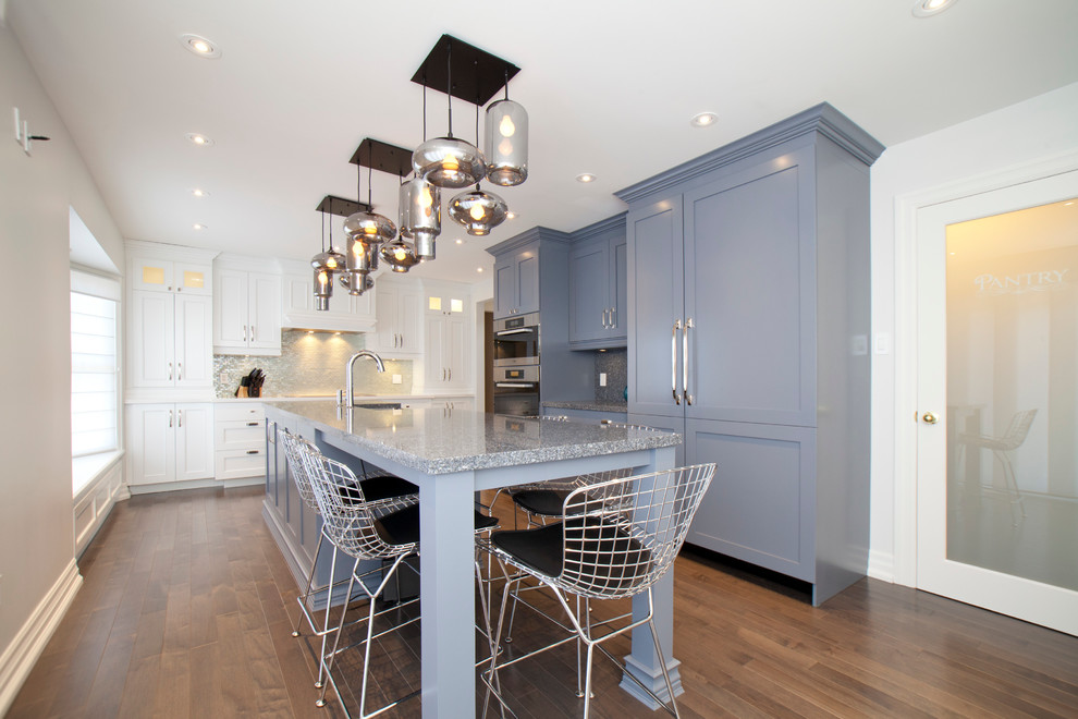 Klassische Küche mit Landhausspüle, Quarzwerkstein-Arbeitsplatte, Rückwand aus Glasfliesen, Elektrogeräten mit Frontblende, braunem Holzboden und Kücheninsel in Toronto