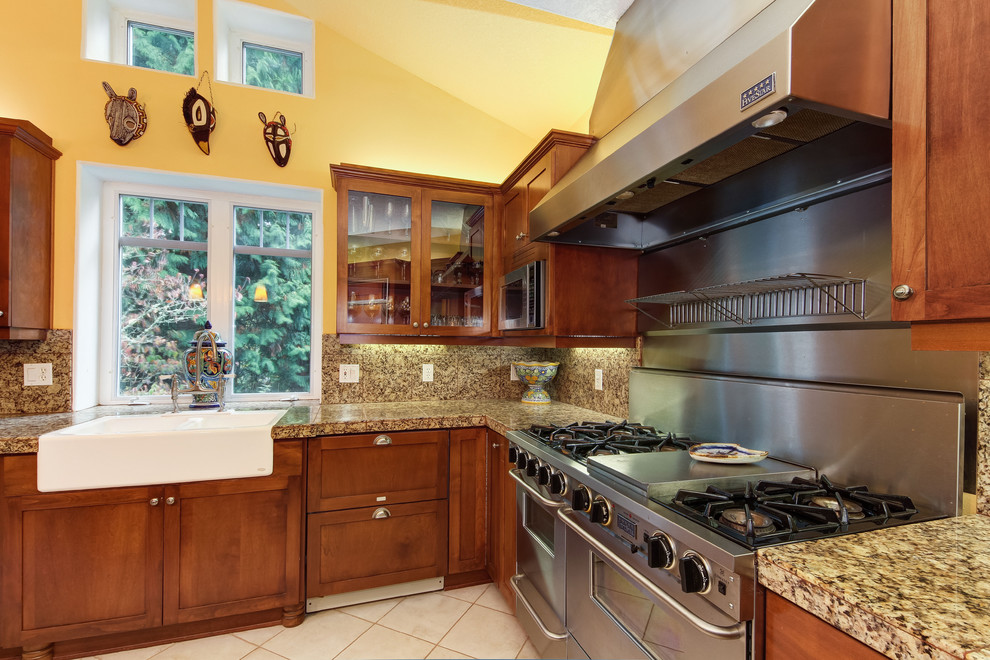 Modelo de cocina clásica con armarios tipo vitrina, electrodomésticos de acero inoxidable, fregadero sobremueble y encimera de granito