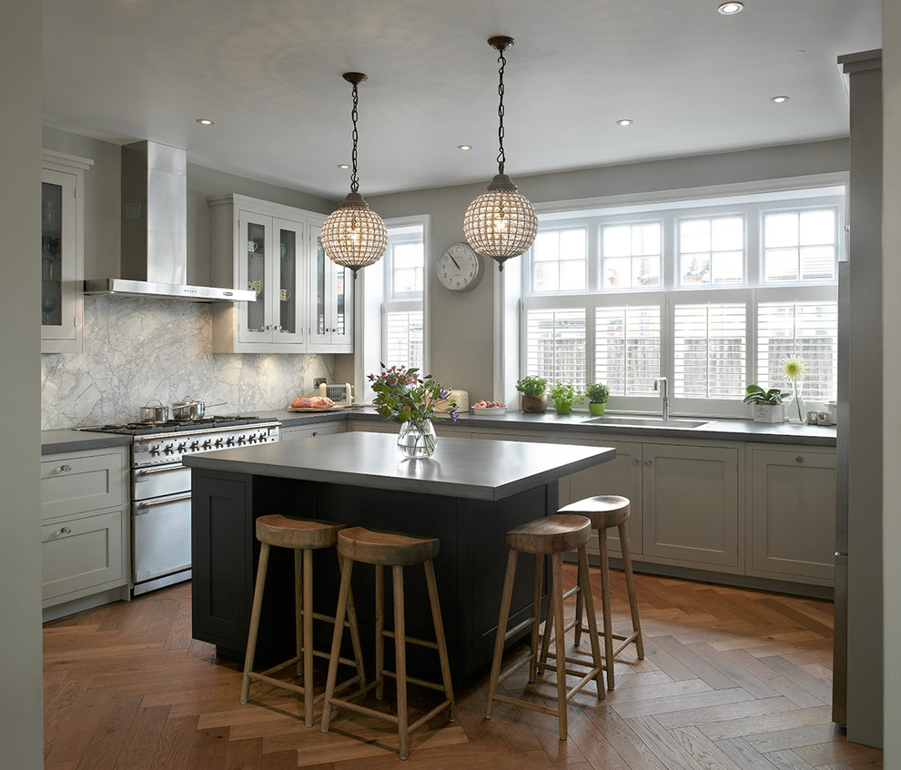 Photo of a medium sized traditional u-shaped enclosed kitchen in London with grey cabinets, marble splashback, stainless steel appliances, medium hardwood flooring, an island, shaker cabinets, grey splashback, brown floors and grey worktops.