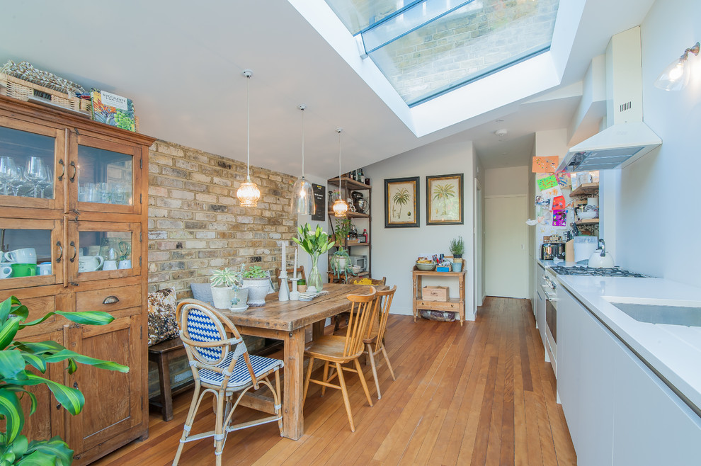 Imagen de cocina comedor lineal clásica renovada de tamaño medio sin isla con fregadero bajoencimera, armarios con paneles lisos, puertas de armario beige, encimera de cuarcita, electrodomésticos de colores y suelo de madera en tonos medios